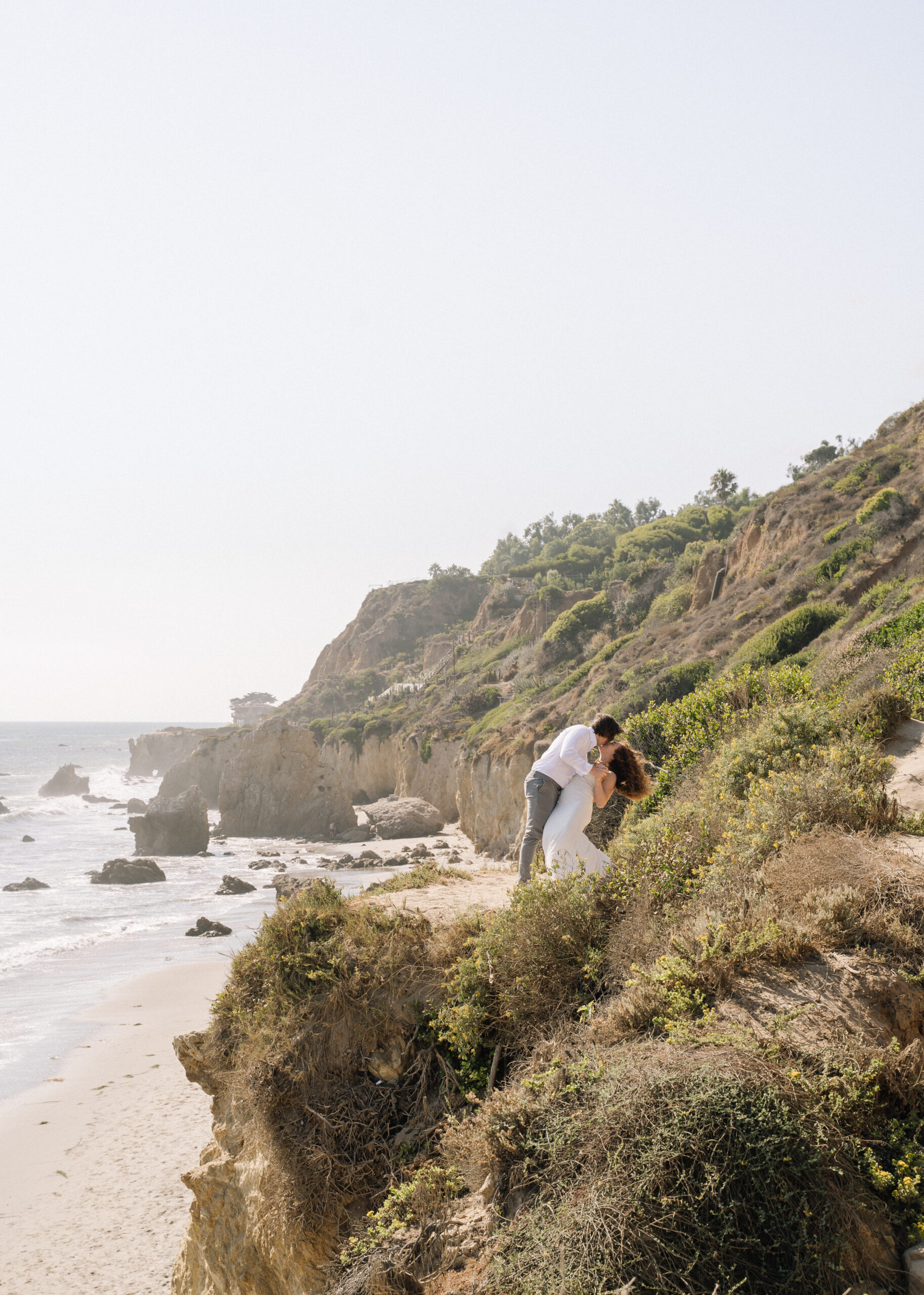 Bride and groom kiss on the cliffs of El Matador Beach