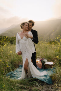 Couple poses for portraits at sunset in Malibu with picnic